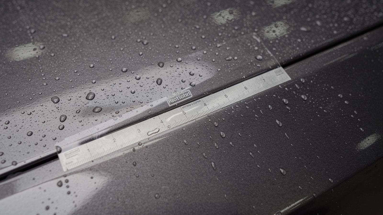 Macro view of a paint protection film edge on a car hood with a paint depth gauge reading